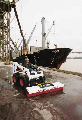 Skid steer with mega broom sweeping port area