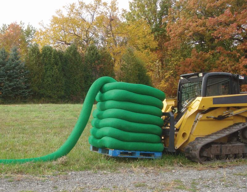 Pallet of coiled Filtrexx SiltSoxx silt socks staged beside a skid steer with fall foliage in the background

