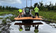 Crew using a skid steer to install MegaDeck HD+ ground protection mats over wet, flooded terrain
