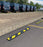 Black and yellow rubber wheel stops installed in a commercial parking lot lined with Amazon delivery vans
