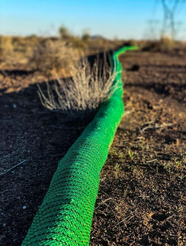 Close-up of a silt sock installed for erosion control in desert soil at sunrise
