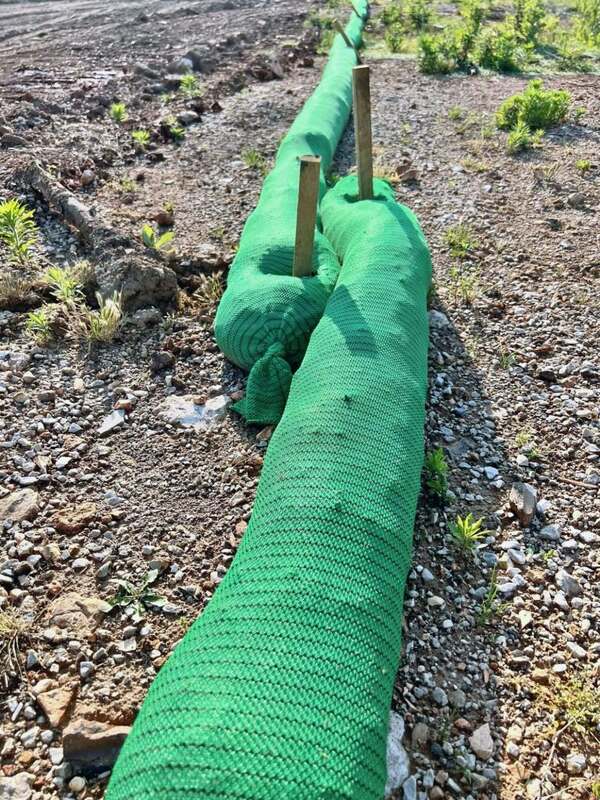 Close-up of staked silt sock ends used for perimeter erosion control on a construction site
