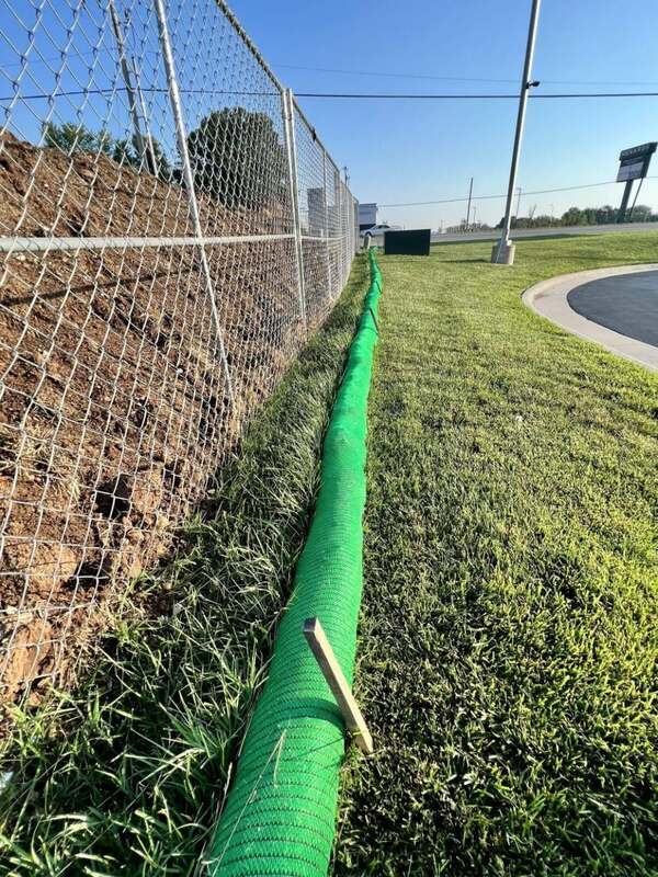 Green silt sock installed for perimeter control along a chain link fence at a new construction site
