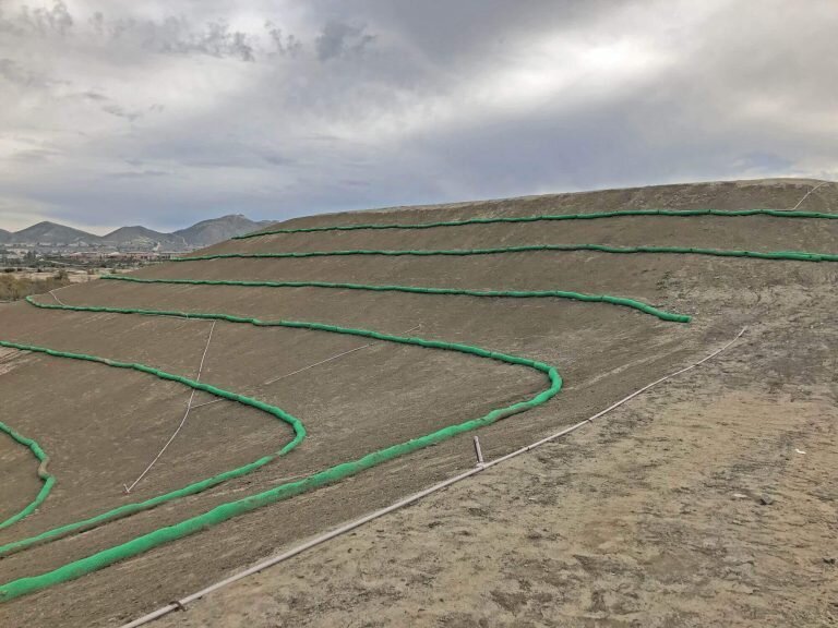 Curved silt socks installed as slope interruption rows on a large graded hillside
