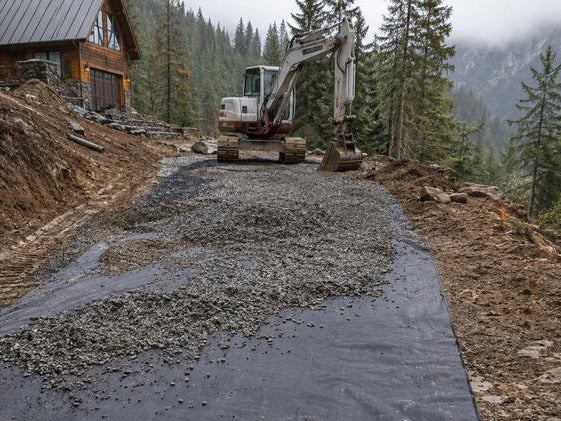 Woven geotextile driveway fabric beneath a gravel driveway
