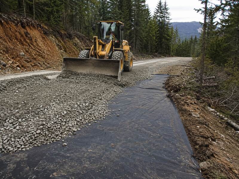 Woven geotextile fabric separating soil from gravel on a driveway
